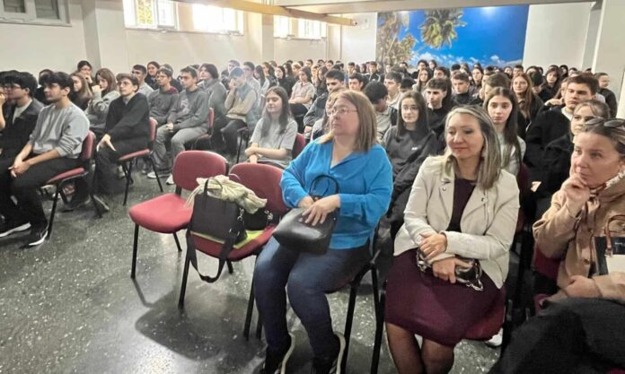 Gençler ve katılımcılar, eğitim ve seminerler için düzenlenmiş iç mekanda toplantı ortamında toplanmış.